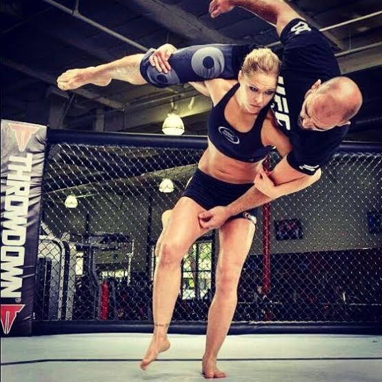 Ronda Rousey executing a judo hip throw on a training partner in a gym