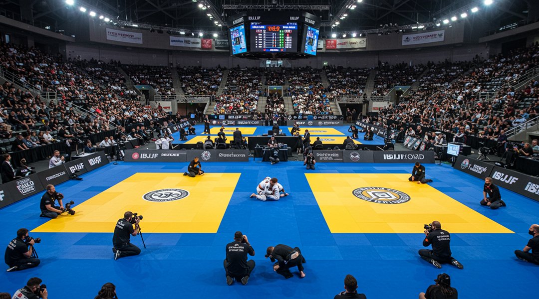 Aerial view IBJJF World Championship competition arena with elite black belt Brazilian Jiu-Jitsu athletes competing on official blue mats surrounded by packed crowd